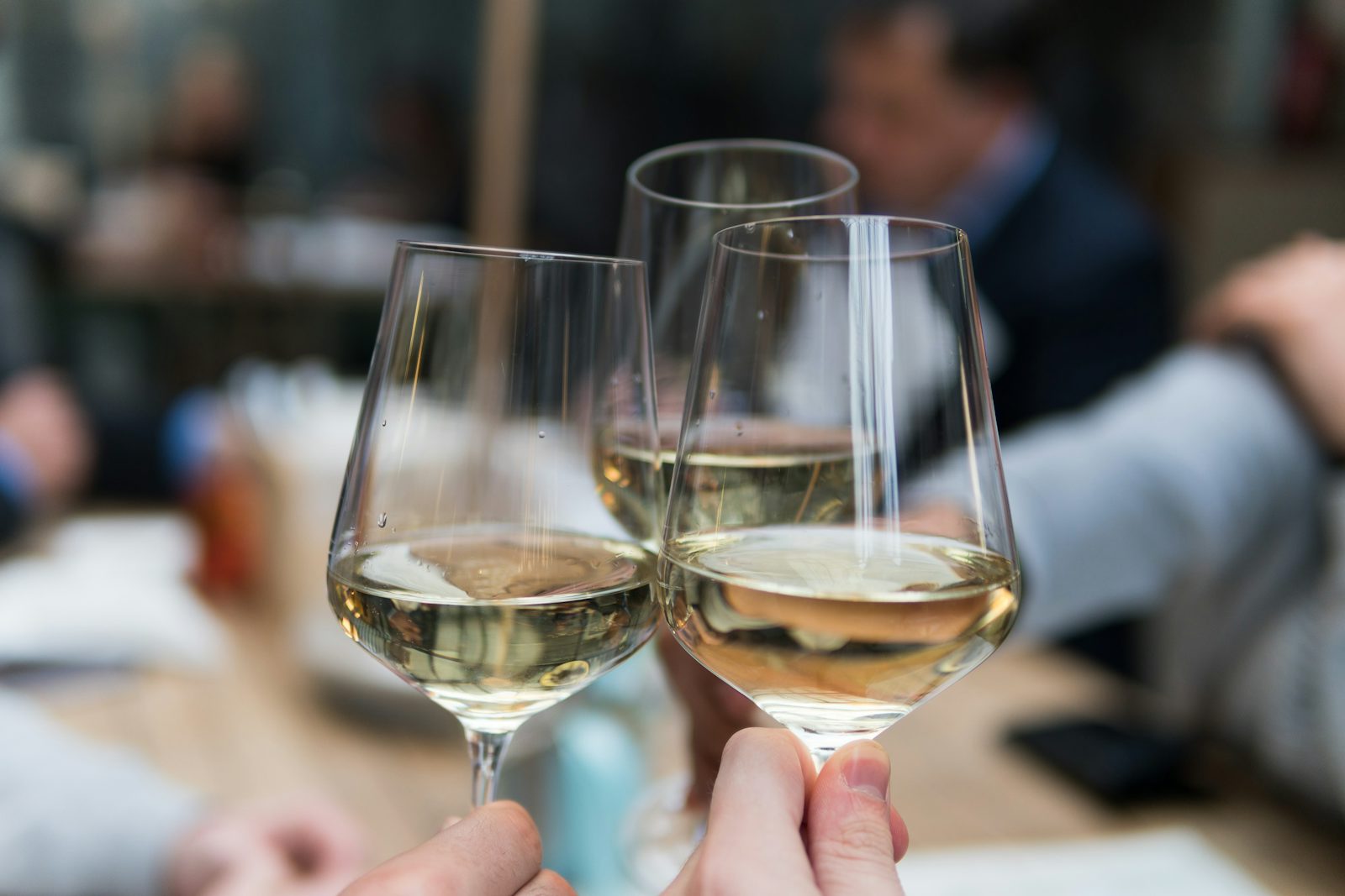 Three people toasting with crystal wine glasses in celebration