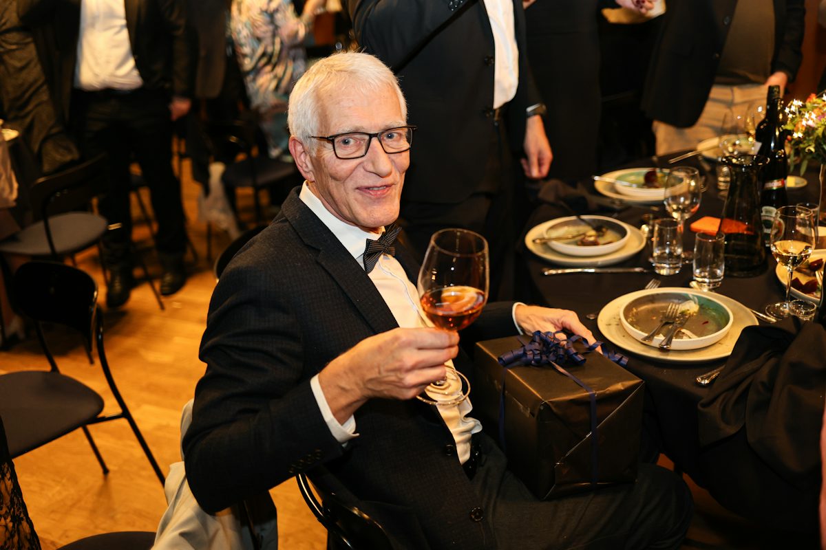 Man in tuxedo holding wine glass at formal dinner